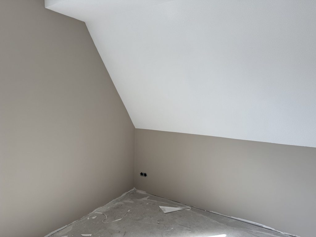 Zolderkamer in een nieuwbouwwoning met een schuine wand, strak afgewerkt in een lichte tint