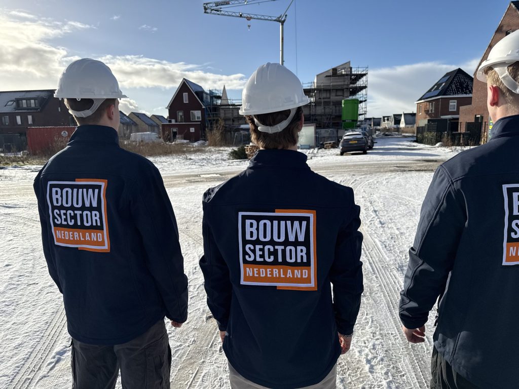 Drie vakmensen van Bouwsector Nederland met witte helm bij nieuwbouwhuizen in aanbouw