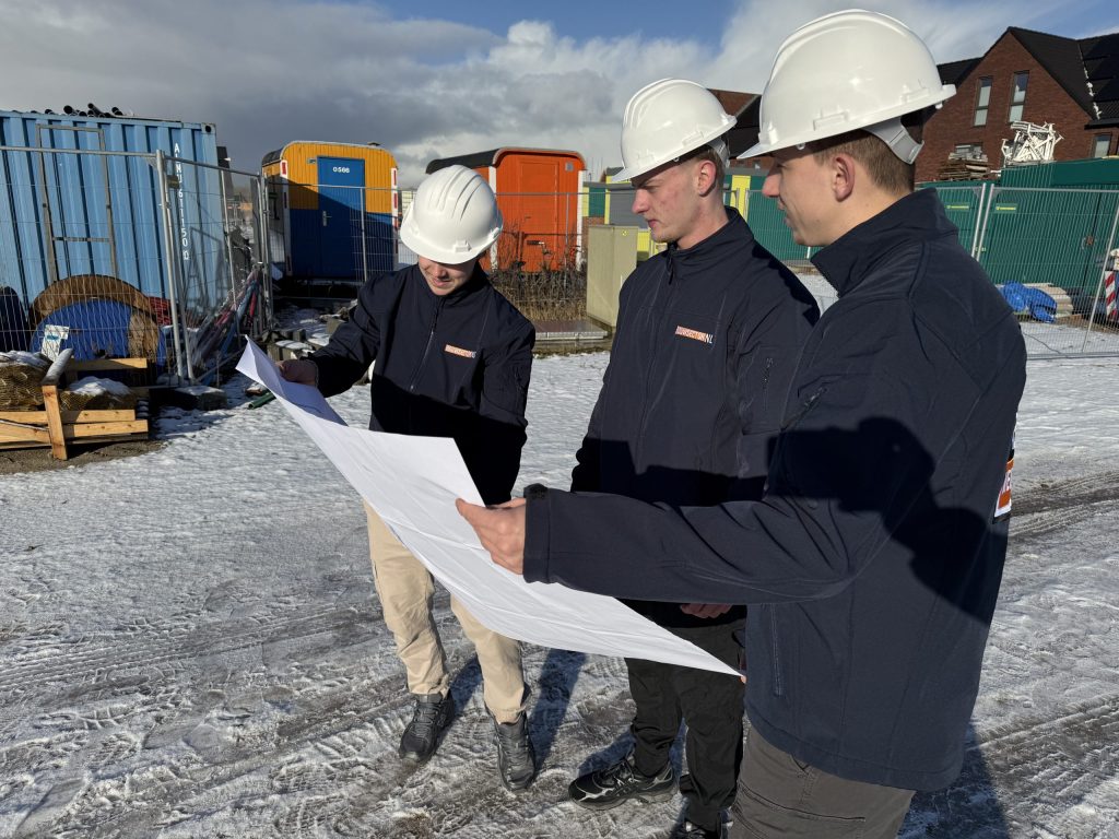 Vakmensen van Bouwsector Nederland bekijken een bouwtekening op een nieuwbouwlocatie